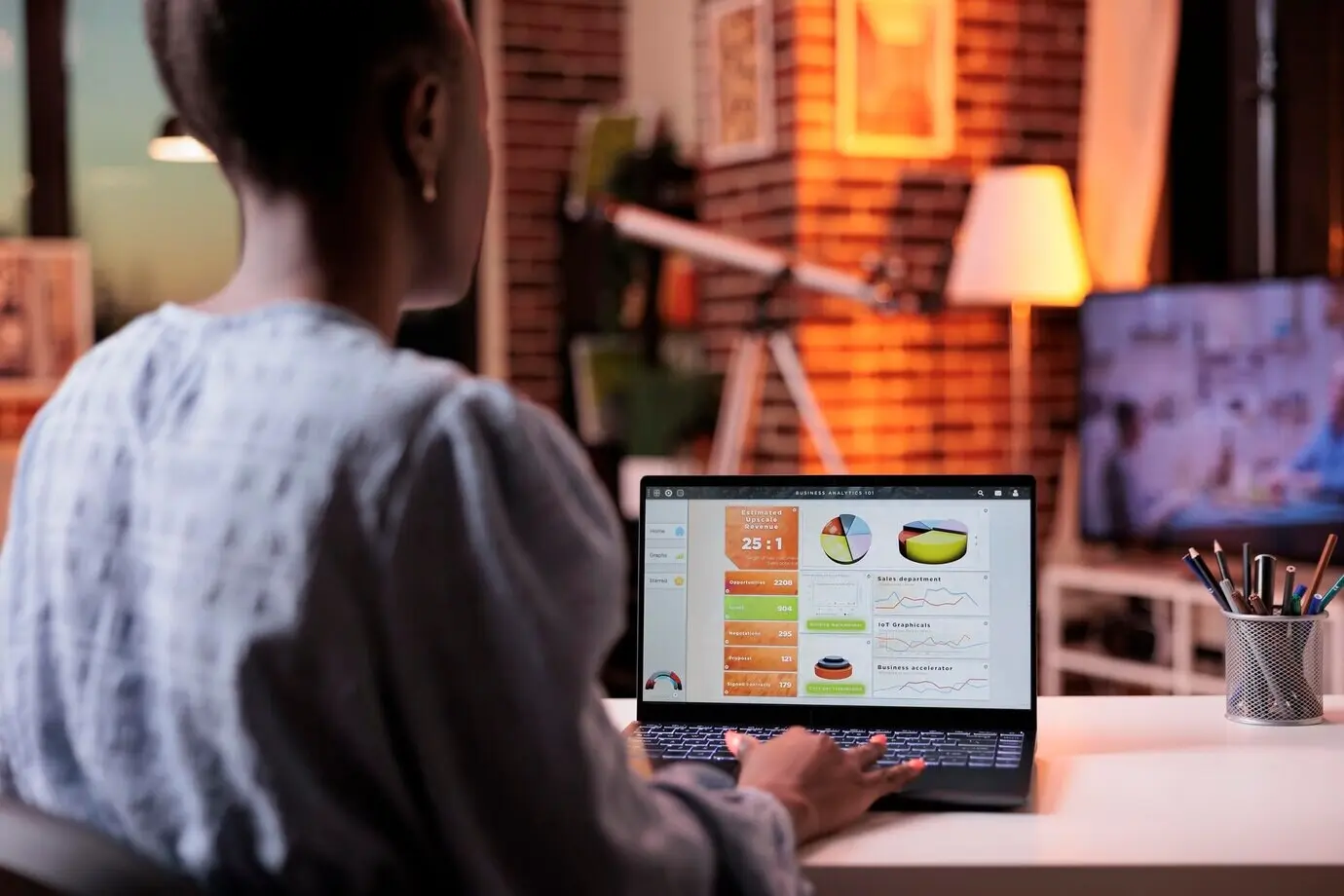 Unternehmensmitarbeiter analysiert Diagramme und Grafiken aus der Marketingforschung des Unternehmens und blickt am Abend im Homeoffice auf den Laptopbildschirm. Auf dem Computer liegen Daten zu Ergebnissen geschäftlicher Forschung vor.